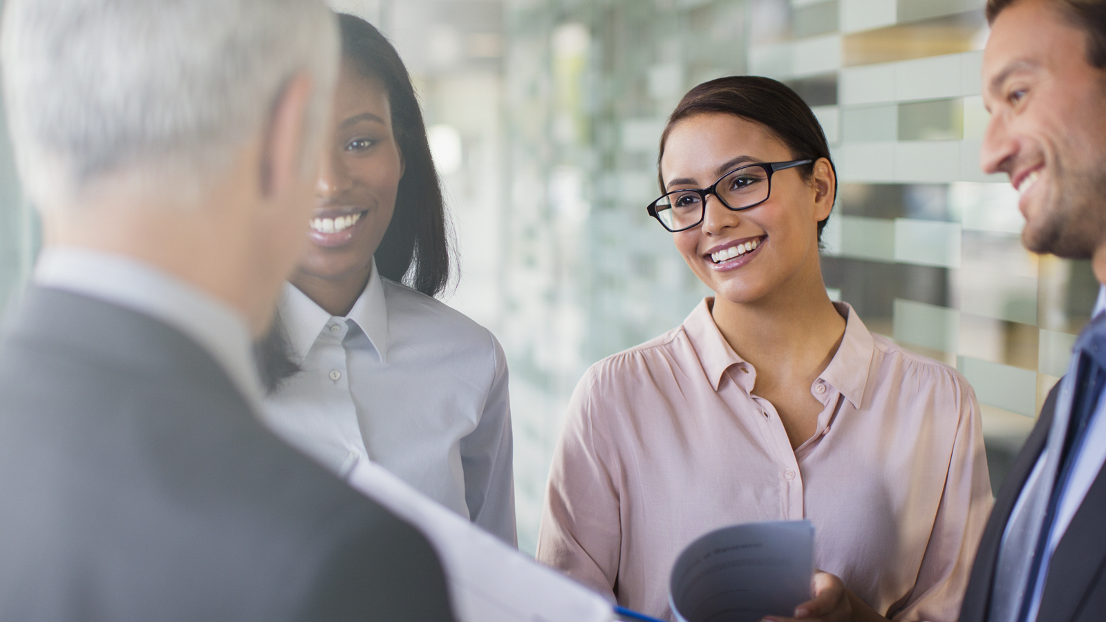Business men and women exchanging greetings in office. Business men and women exchanging greetings in office.