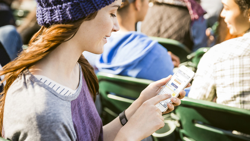 Woman looking at her mobile phone with Visa Checkout on the screen.